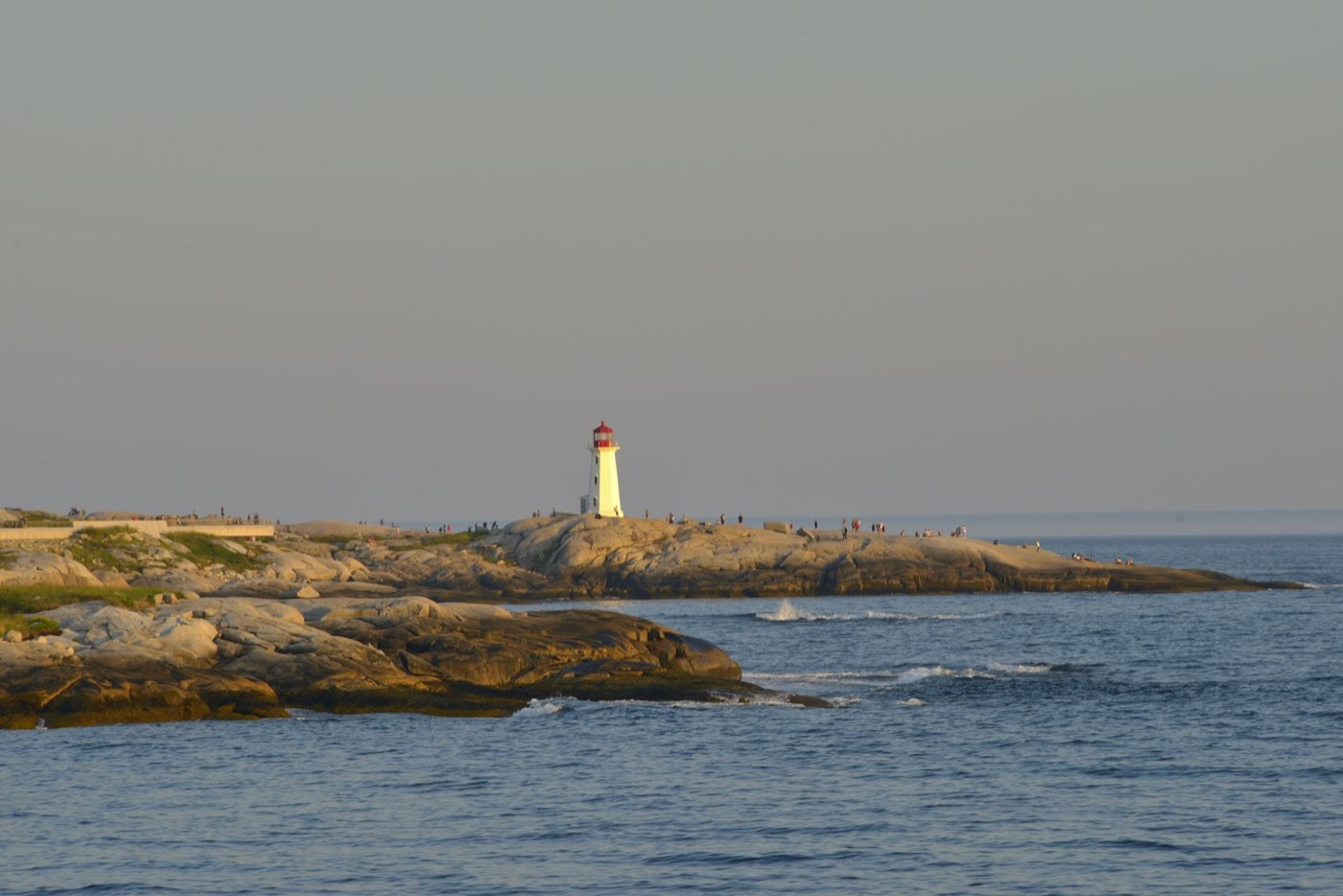 A lighthouse on a rocky Atlantic coastline in late afternoon light